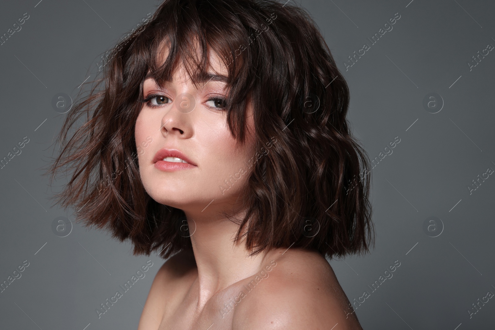 Photo of Portrait of beautiful young woman with wavy hairstyle on grey background