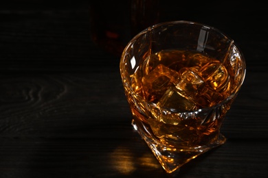 Golden whiskey in glass with ice cubes on table. Space for text