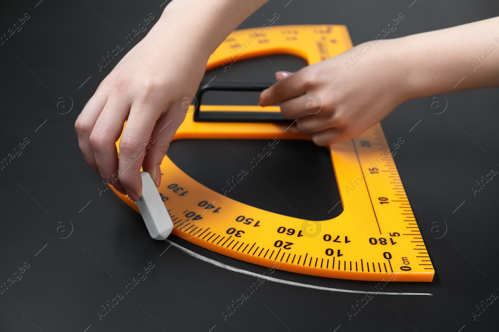 Photo of Woman drawing with chalk and protractor on blackboard, closeup