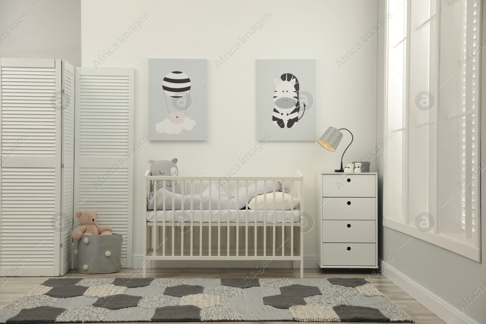 Photo of Stylish baby room interior with crib and chest of drawers