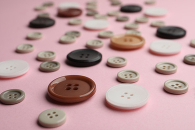 Photo of Many sewing buttons on pink background, closeup view