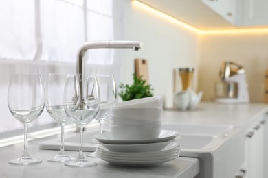 Photo of Different clean dishware and glasses on countertop near sink in kitchen