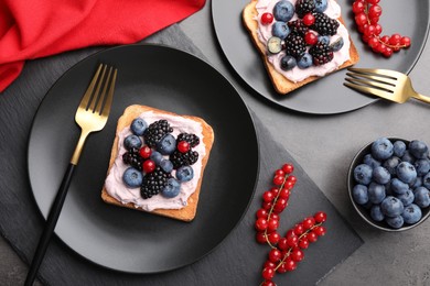 Photo of Tasty sandwiches with cream cheese and berries on grey table, flat lay