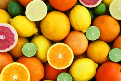 Photo of Many different whole and cut citrus fruits as background, top view