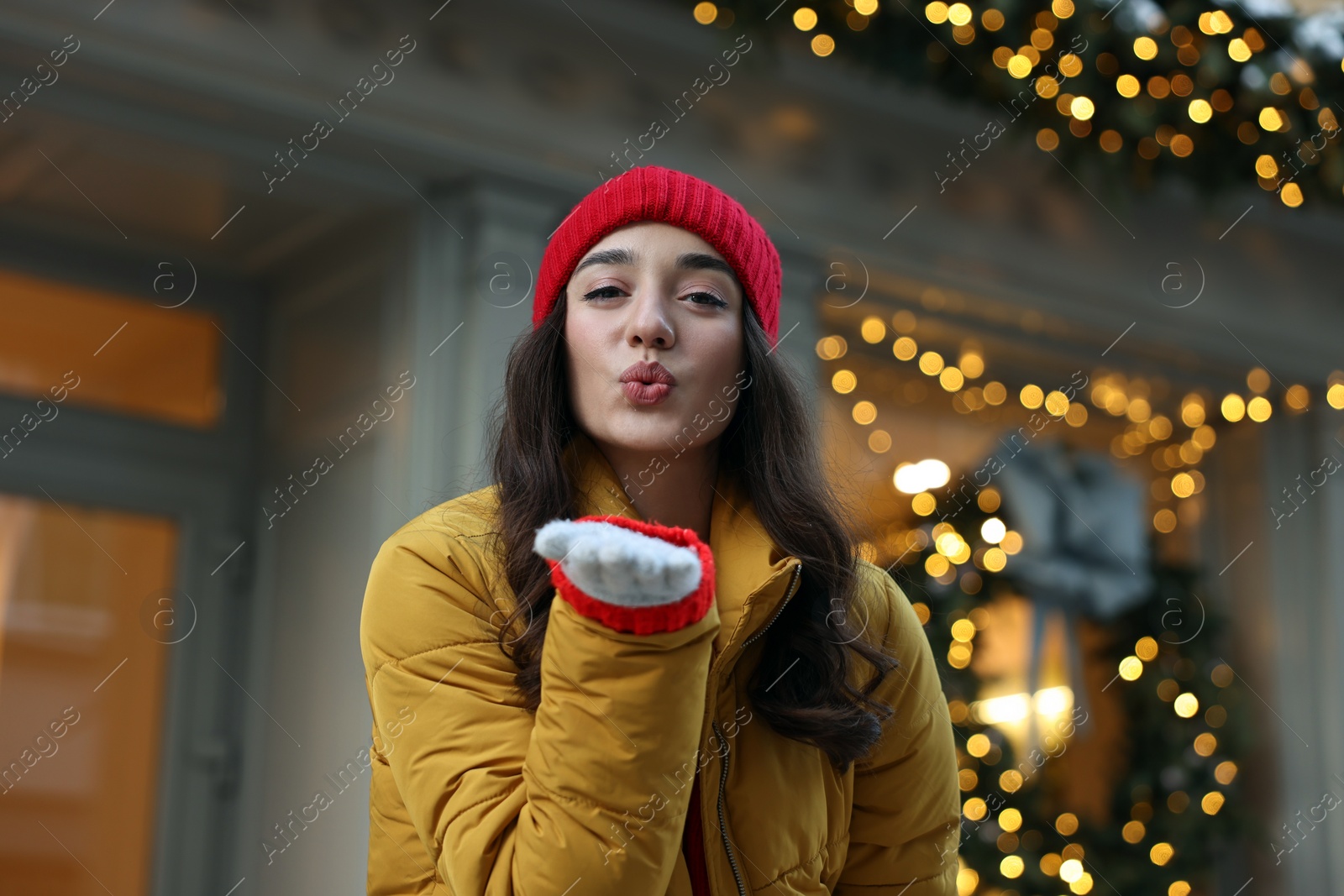 Photo of Portrait of beautiful woman blowing kiss on city street in winter