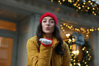 Photo of Portrait of beautiful woman blowing kiss on city street in winter