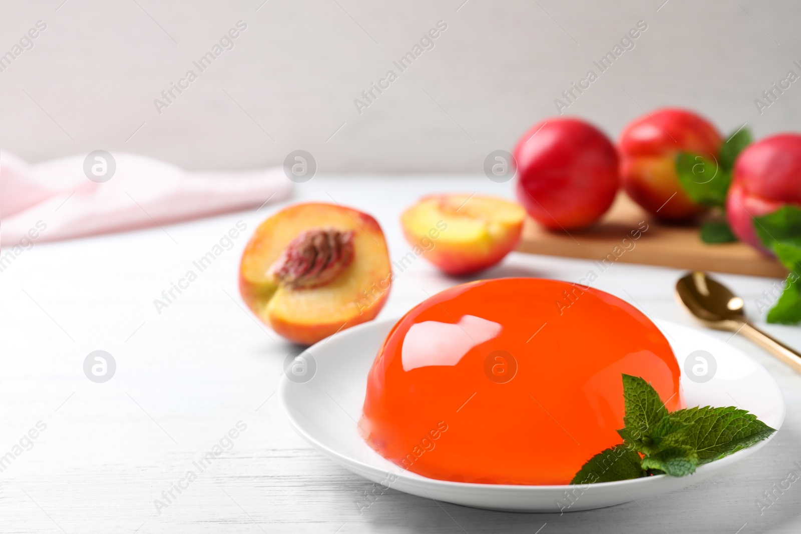 Photo of Delicious orange jelly with mint on white wooden table