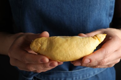 Photo of Woman holding piece of durian on dark background, closeup