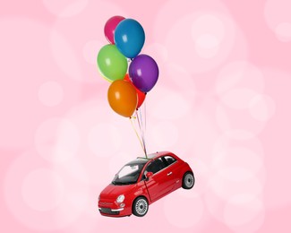 Many balloons tied to toy car flying on pink background