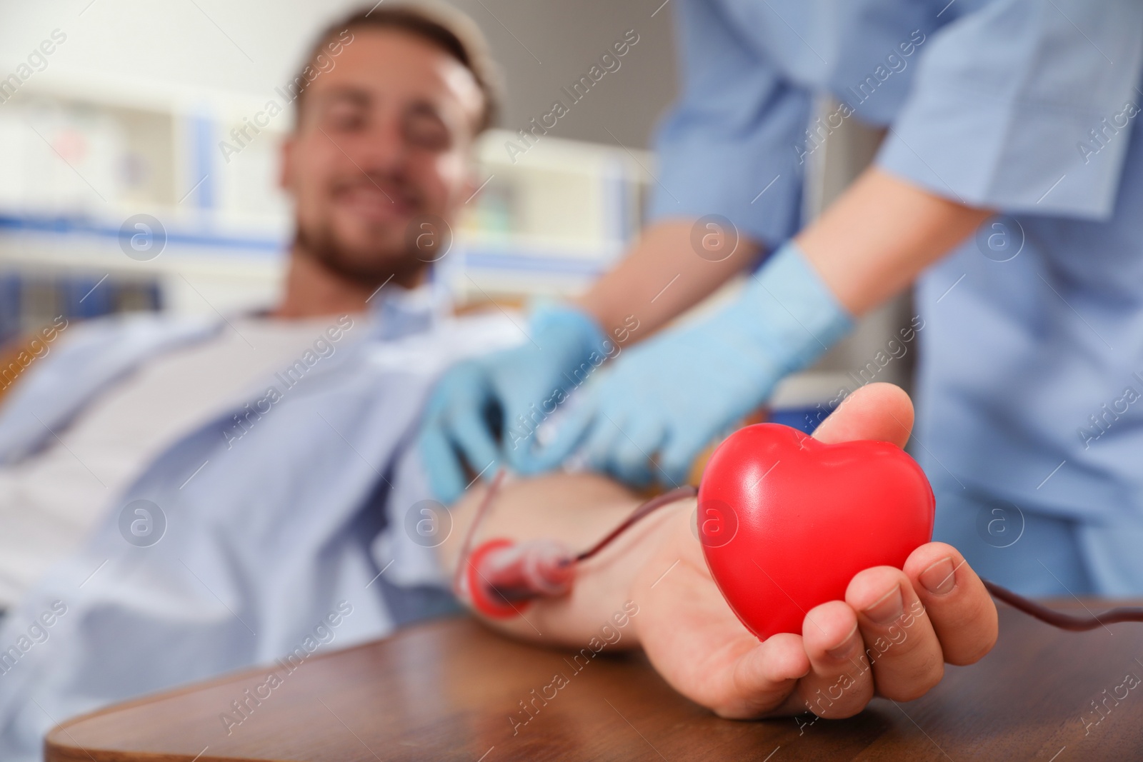 Photo of Young man making blood donation in hospital, focus on hand