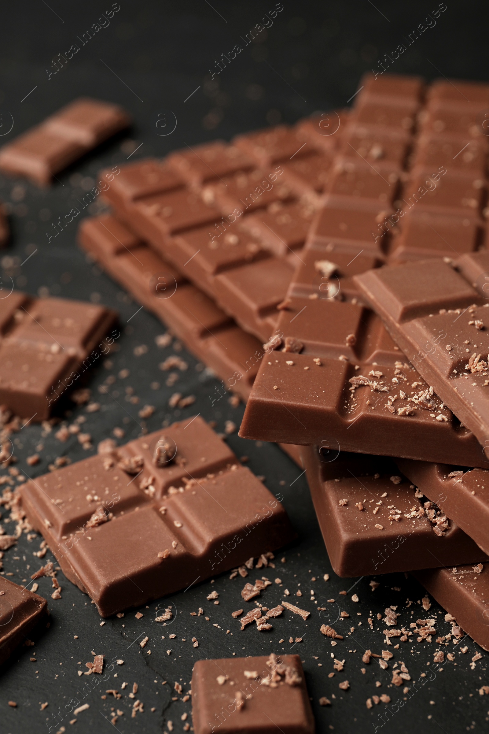 Photo of Pieces of tasty chocolate bars on grey table, closeup