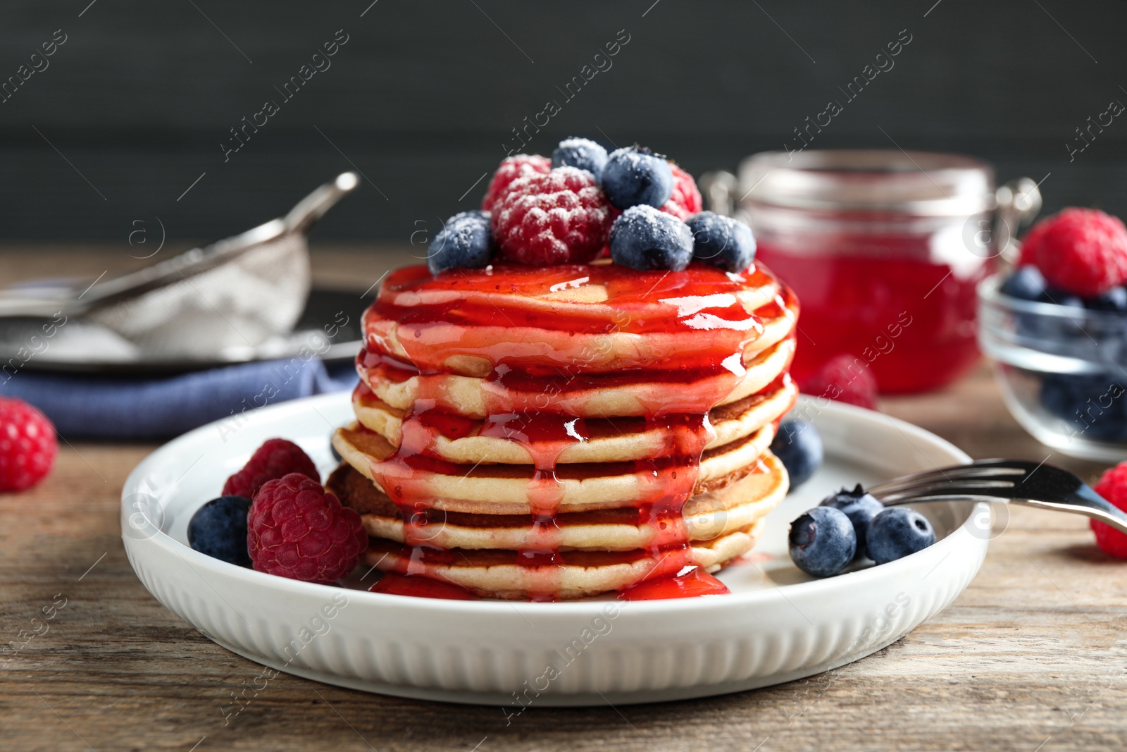 Photo of Delicious pancakes with fresh berries and syrup on wooden table