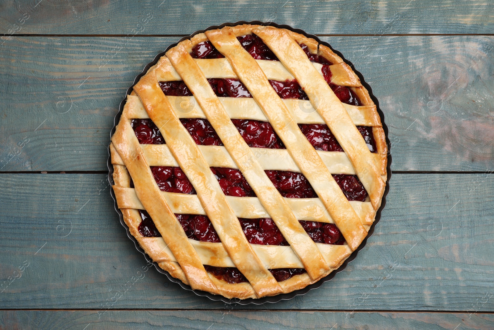 Photo of Delicious fresh cherry pie on light blue wooden table, top view