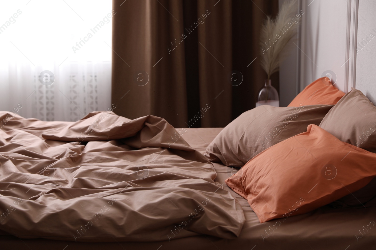 Photo of Bed with orange and brown linens in stylish room