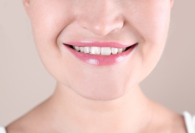 Photo of Young woman with beautiful smile on color background, closeup