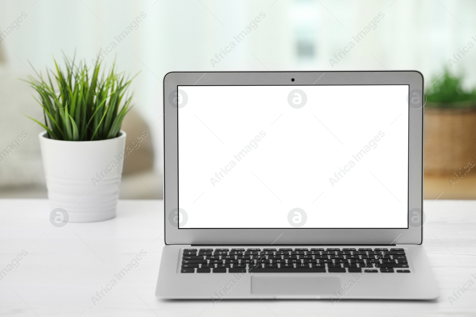 Photo of Laptop with blank screen on table indoors. Space for text