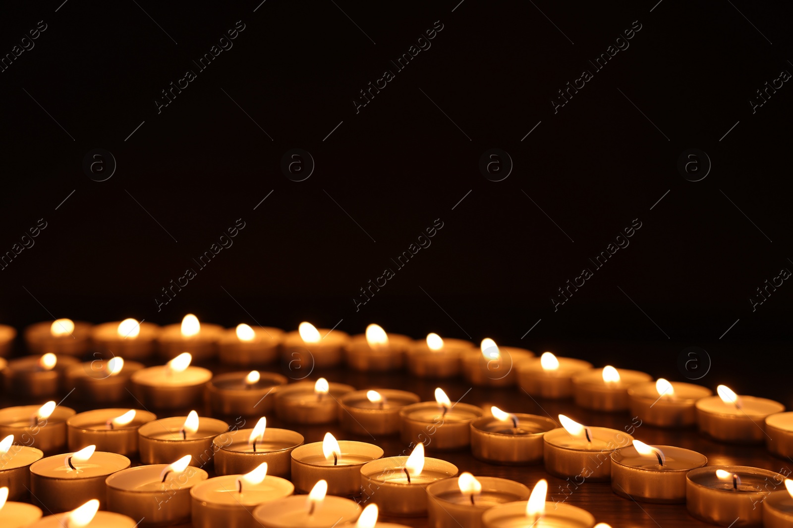 Photo of Burning candles on wooden table against black background