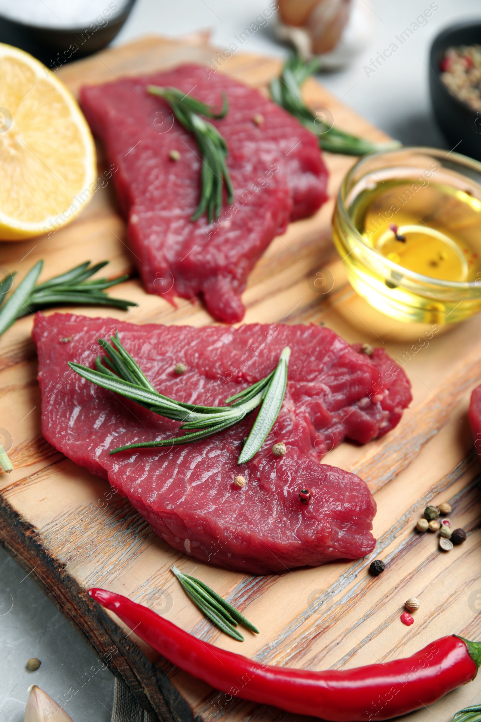 Photo of Fresh raw meat steaks and spices on wooden board, closeup