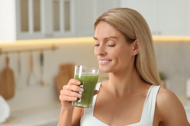 Photo of Woman drinking fresh celery juice in kitchen