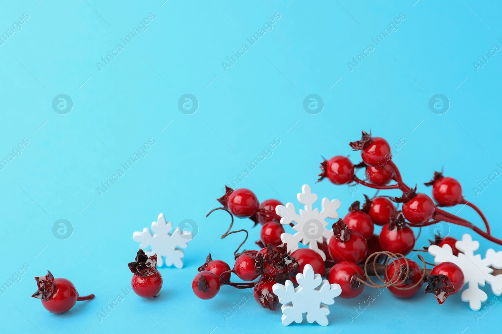 Photo of Decorative branches and snowflakes on light blue background. Winter season