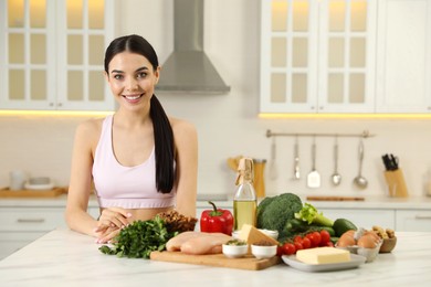 Photo of Happy woman with different products in kitchen. Keto diet
