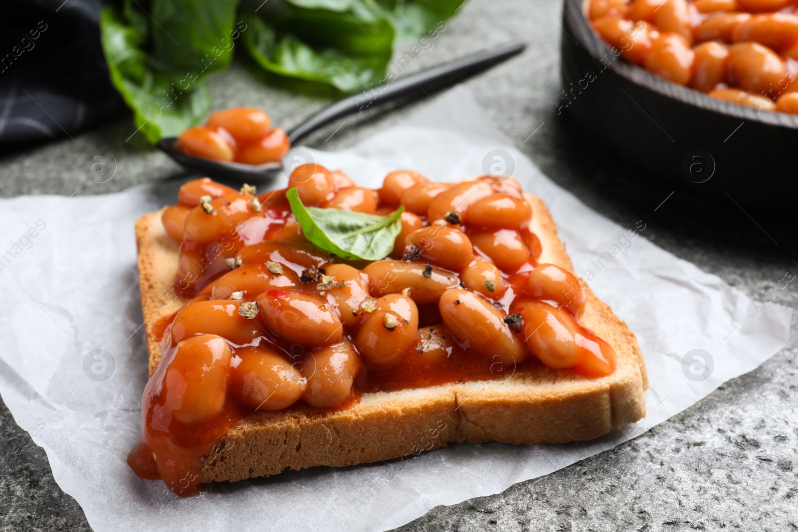 Photo of Toast with delicious canned beans on grey table