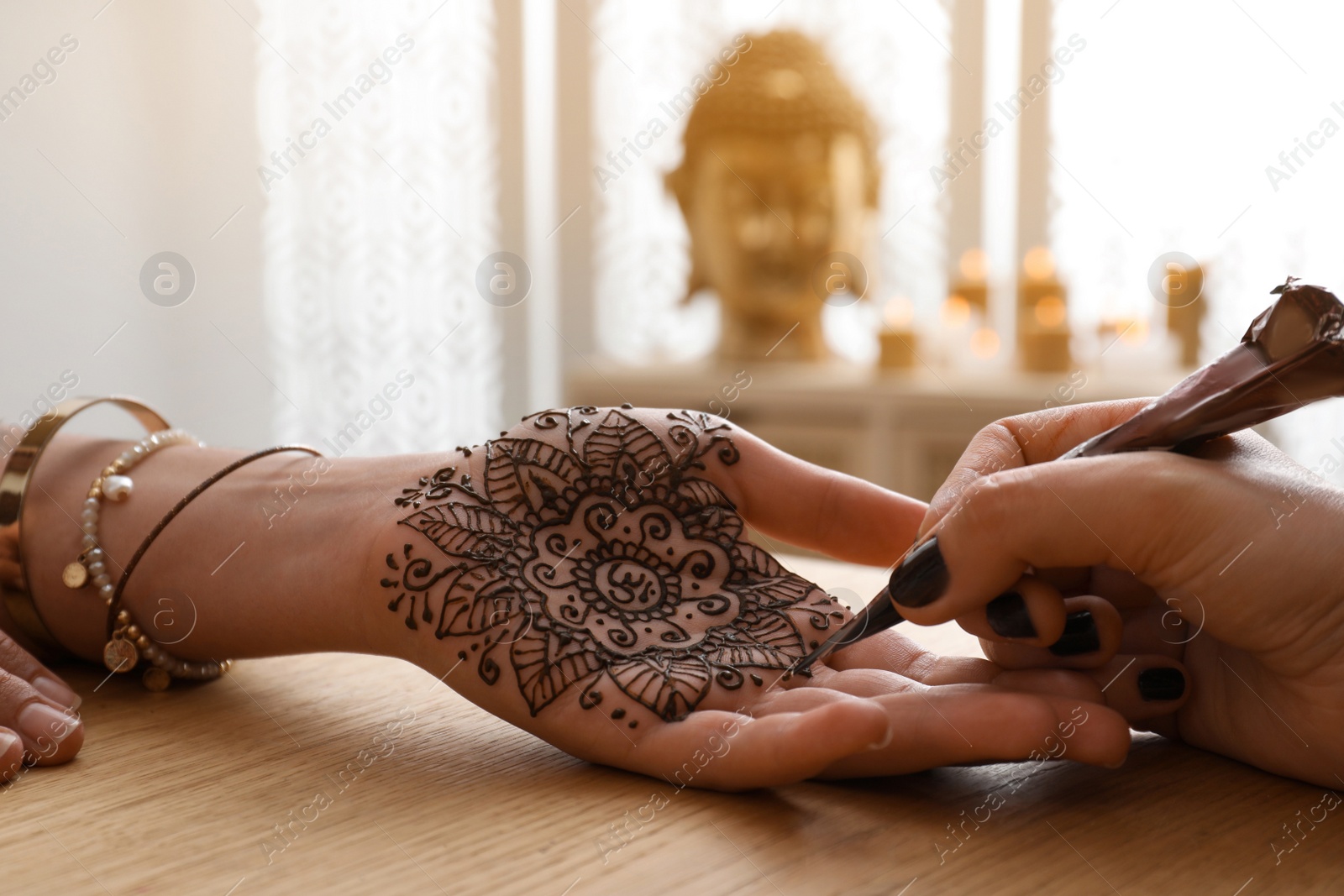 Photo of Professional mehndi master making henna tattoo indoors, closeup