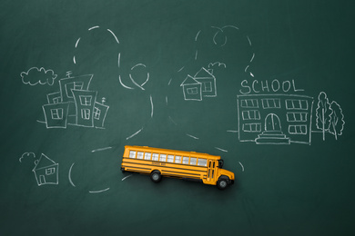 Photo of Yellow school bus and drawing on chalkboard, top view. Transport for students