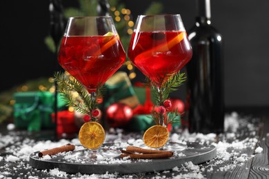 Photo of Christmas Sangria cocktail in glasses and snow on dark wooden table