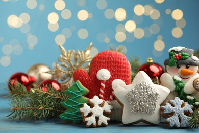 Sweet Christmas cookies and decor on light blue table against blurred festive lights