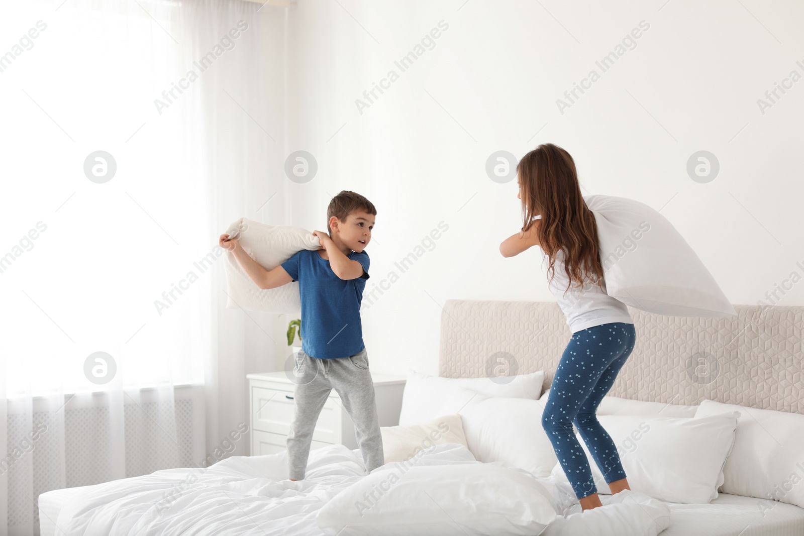 Photo of Happy children having pillow fight in bedroom