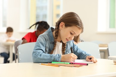 Photo of Portrait of cute little girl studying in classroom at school