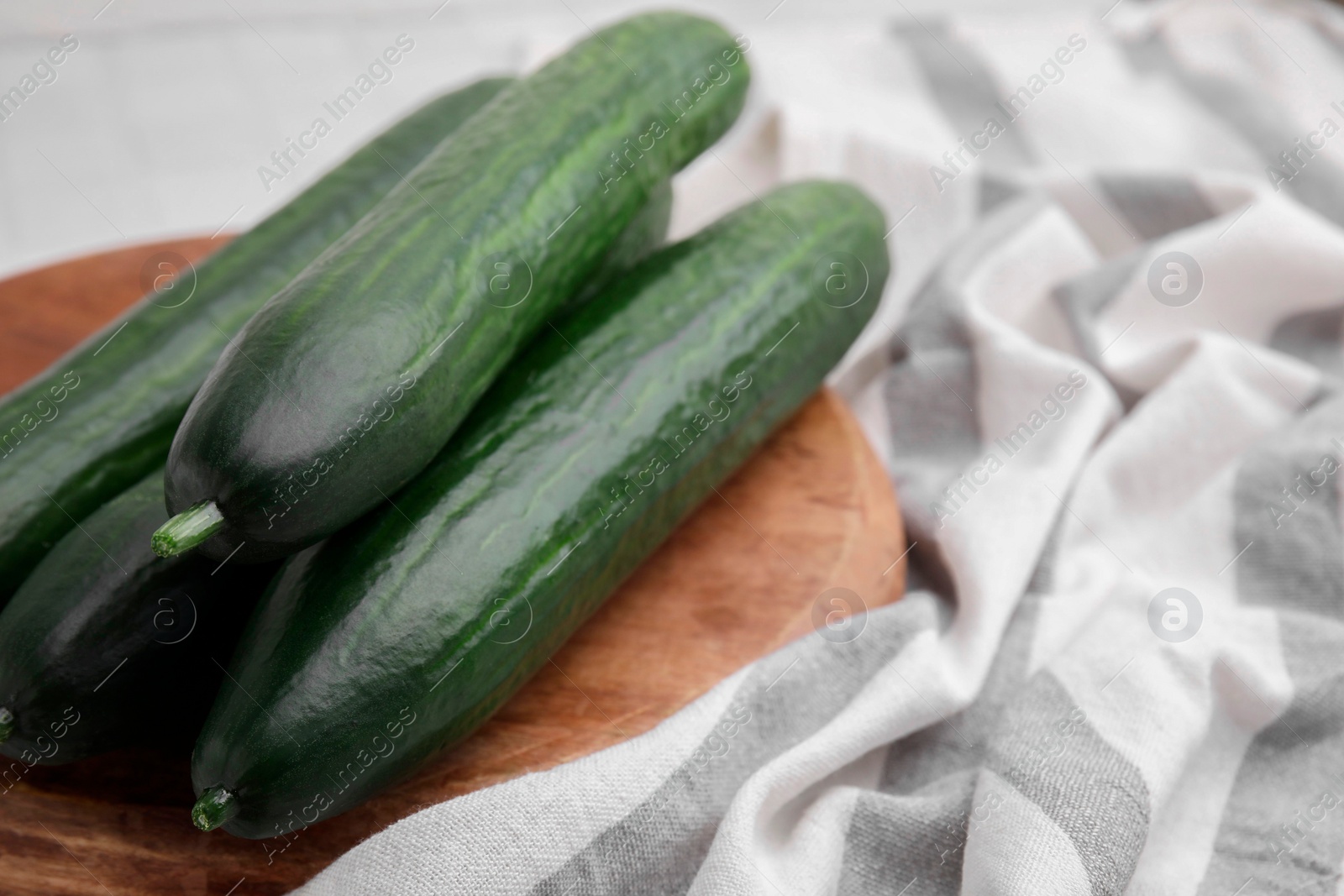 Photo of Fresh cucumbers and cloth on table, closeup