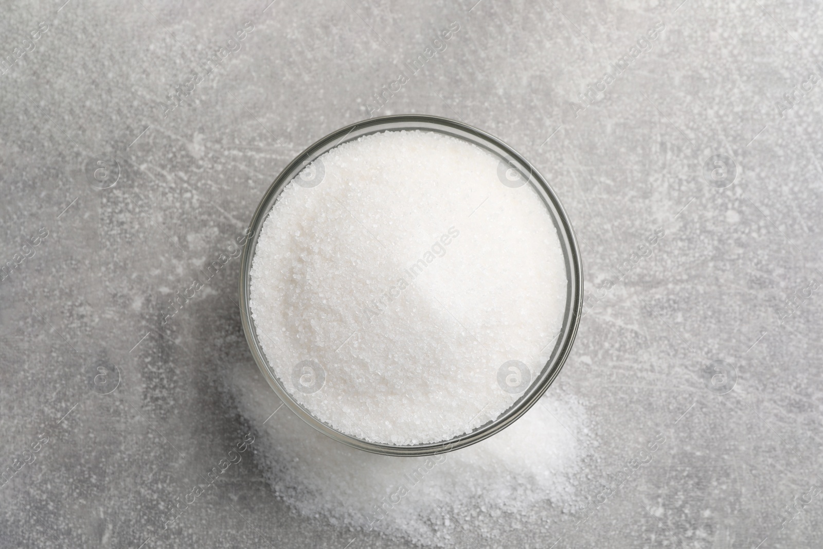 Photo of Granulated sugar on light grey table, top view