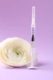 Photo of Cosmetology. Medical syringe and ranunculus flower on violet background