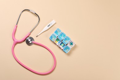 Stethoscope, thermometer and pills on beige background, flat lay. Space for text