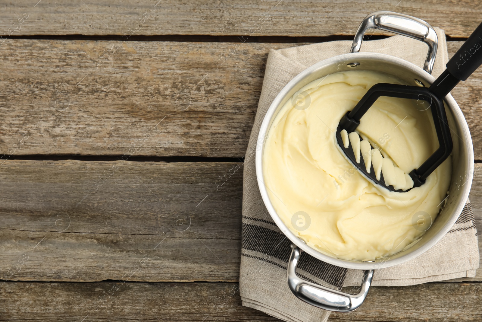 Photo of Pot of freshly cooked homemade mashed potatoes on wooden table, top view. Space for text