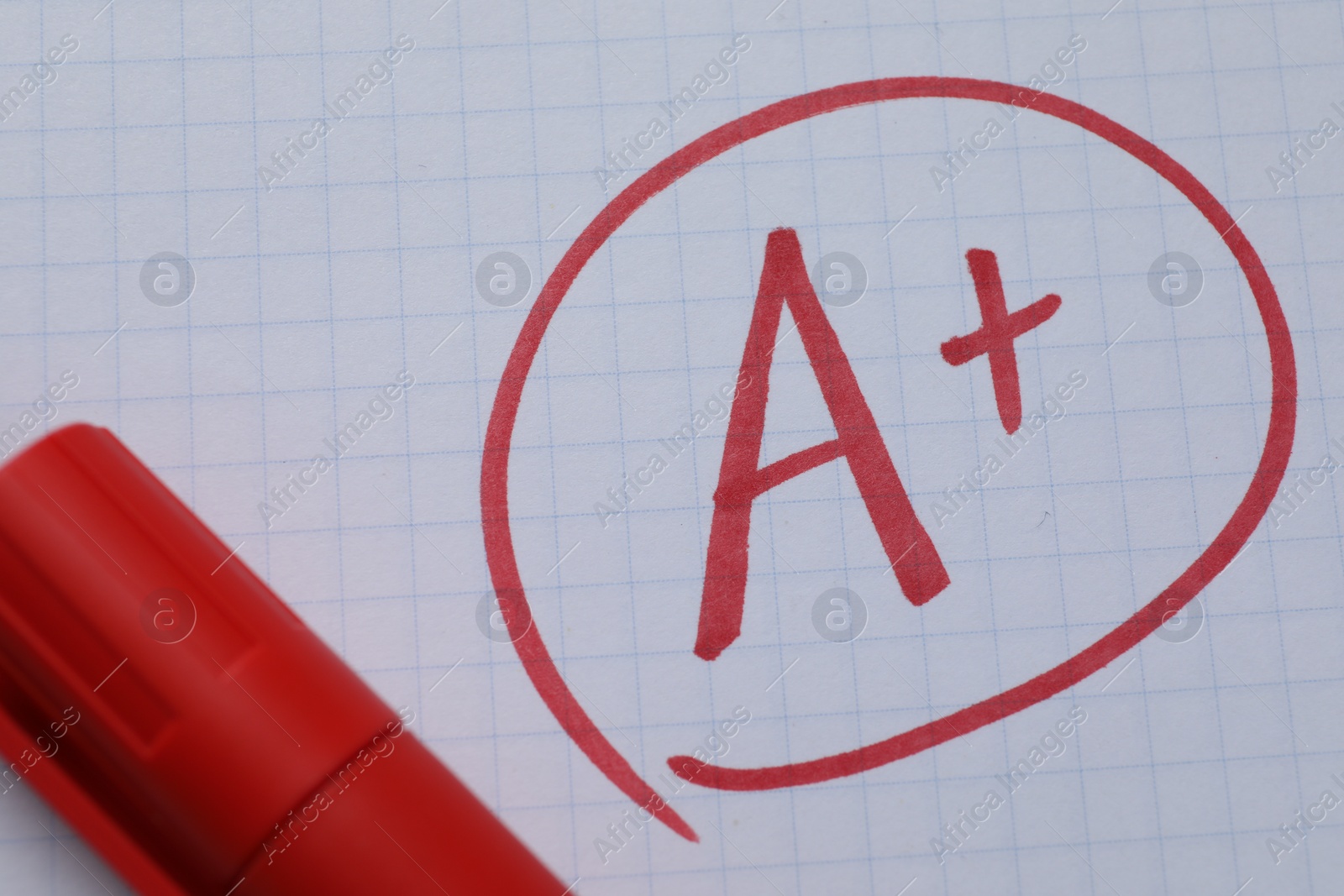 Photo of School grade. Red letter A with plus symbol on notebook paper and marker, top view