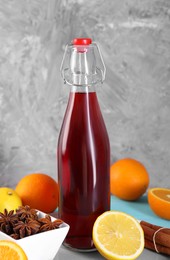 Photo of Bottle of aromatic punch drink and ingredients on light blue table