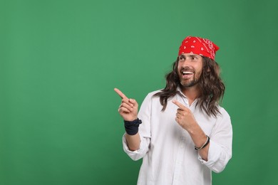 Photo of Hippie man pointing at something on green background, space for text