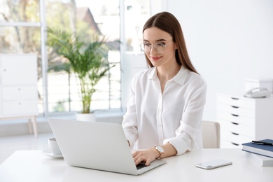 Young businesswoman using laptop at table in office