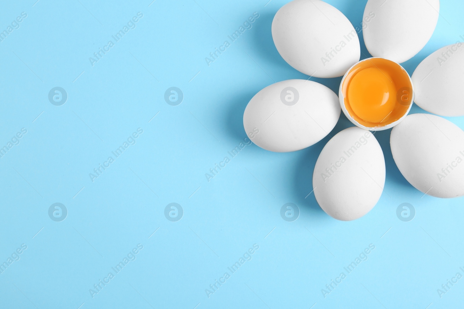 Photo of Fresh raw chicken eggs on light blue background, flat lay. Space for text