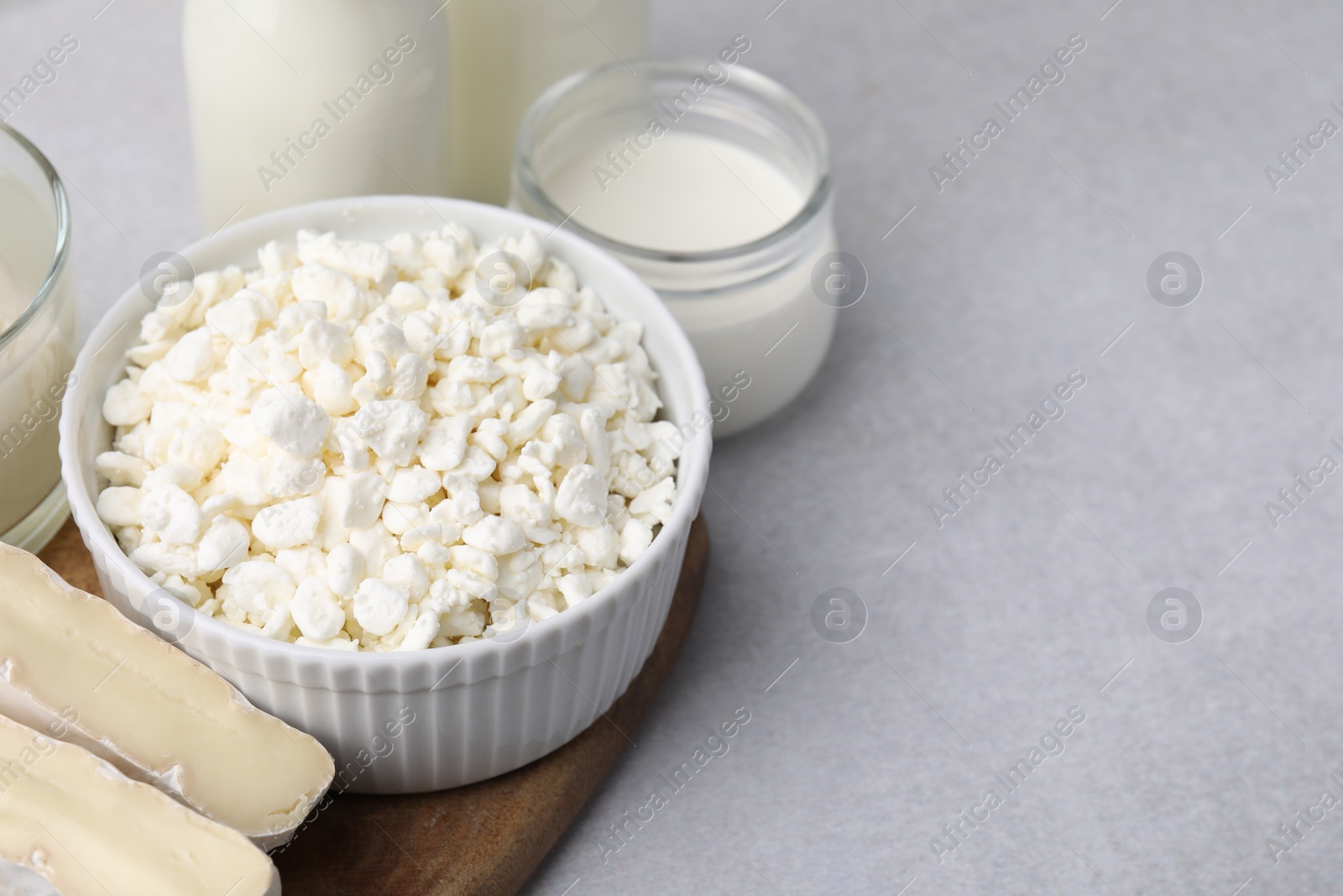 Photo of Fresh cottage cheese and other dairy products on light table. Space for text