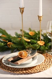 Photo of Festive place setting with beautiful dishware, fabric napkin and dried orange slice for Christmas dinner on white table