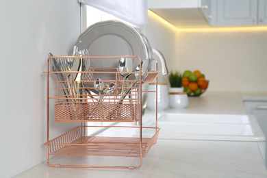 Clean dishes on drying rack in modern kitchen interior