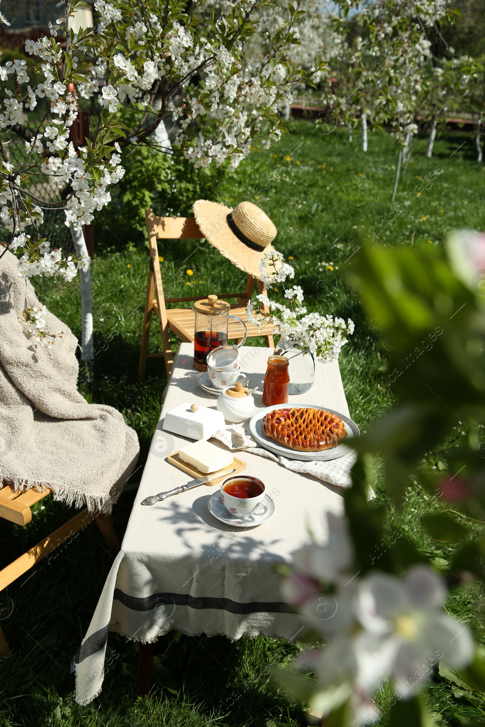 Photo of Beautiful table setting with spring flowers in garden on sunny day