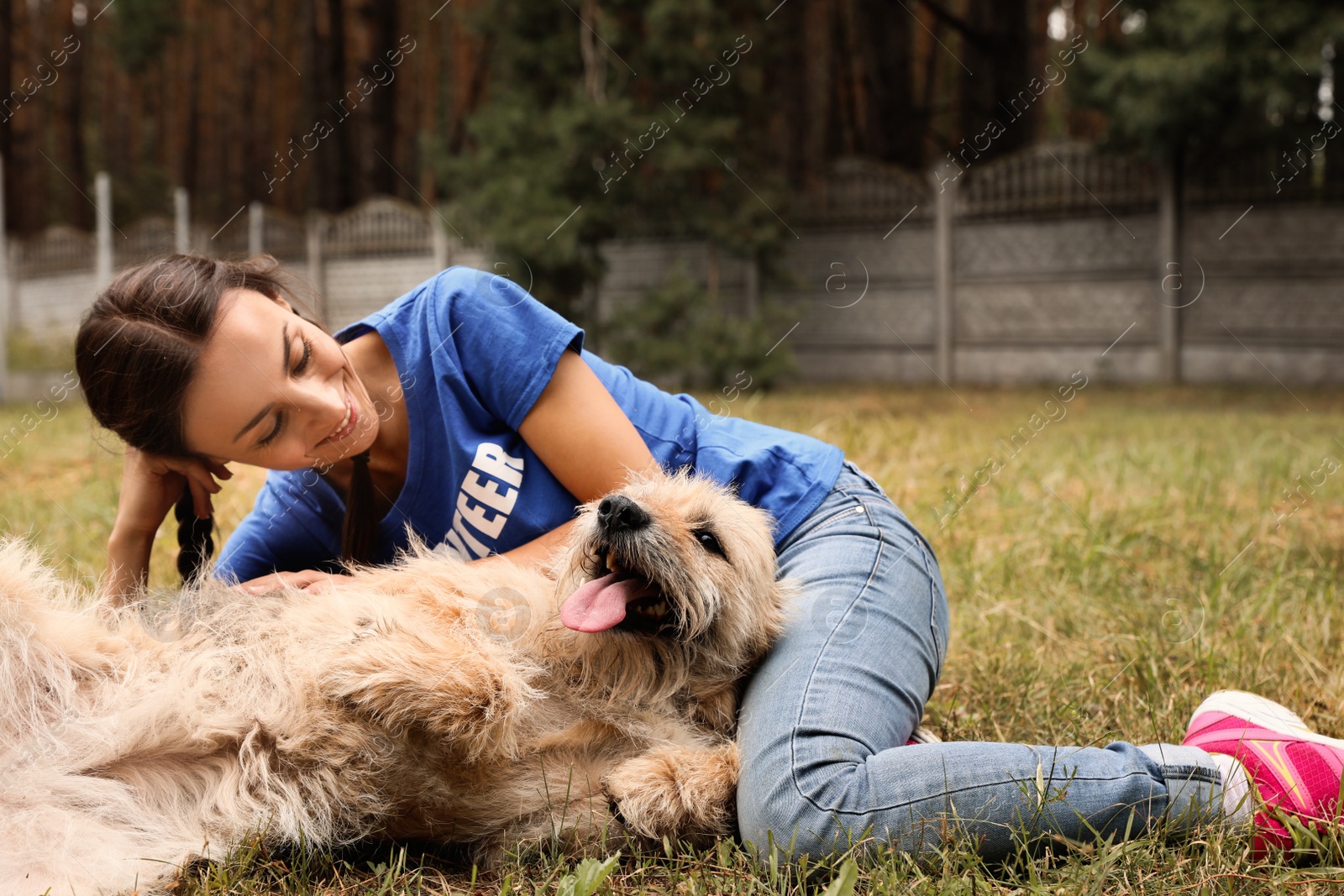 Photo of Female volunteer with homeless dog at animal shelter outdoors