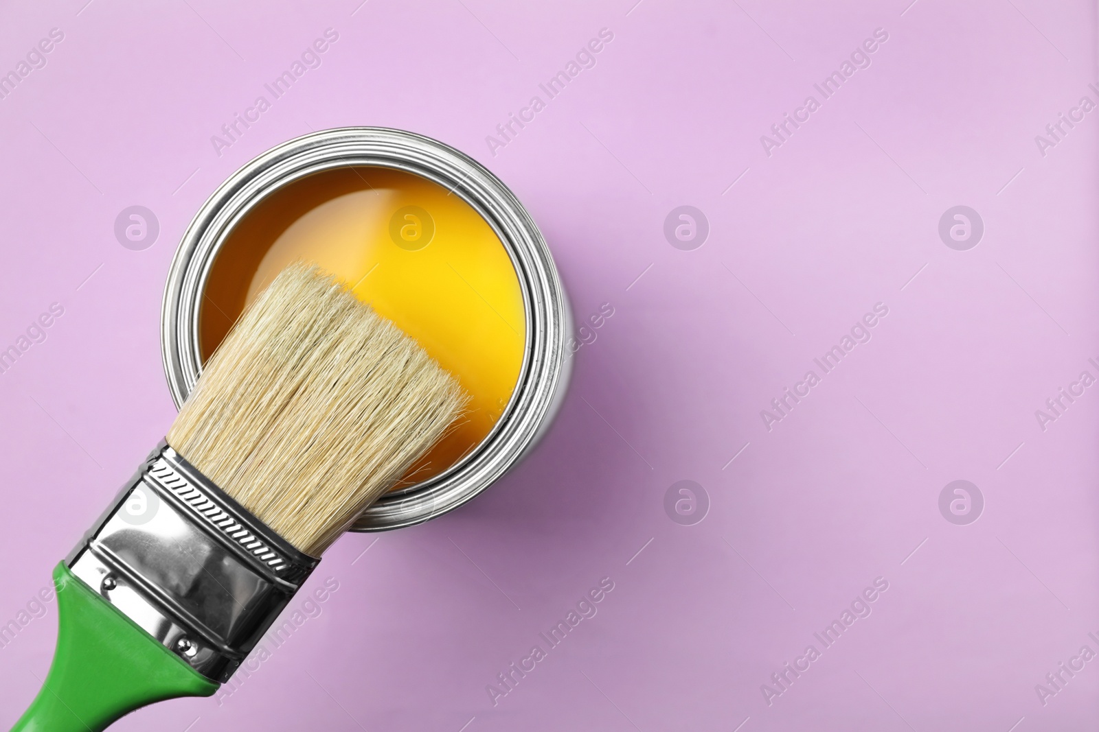 Photo of Open can with paint and brush on color background, top view. Space for text