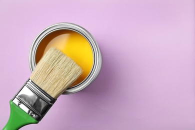 Photo of Open can with paint and brush on color background, top view. Space for text