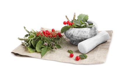 Photo of Cloth and marble mortar with different herbs, berries and pestle on white background